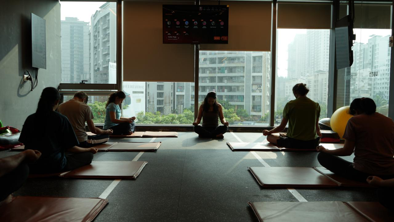 Members meditating together on yoga mats at COREO
